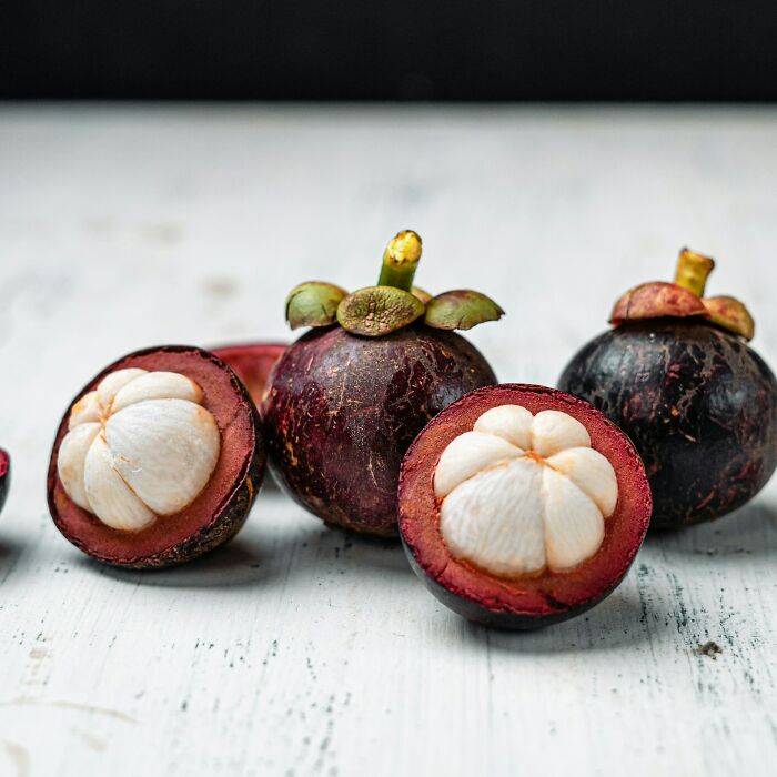 Mangosteen fruit cut open on a white surface, illustrating healthy habits related to nutrition and wellness.