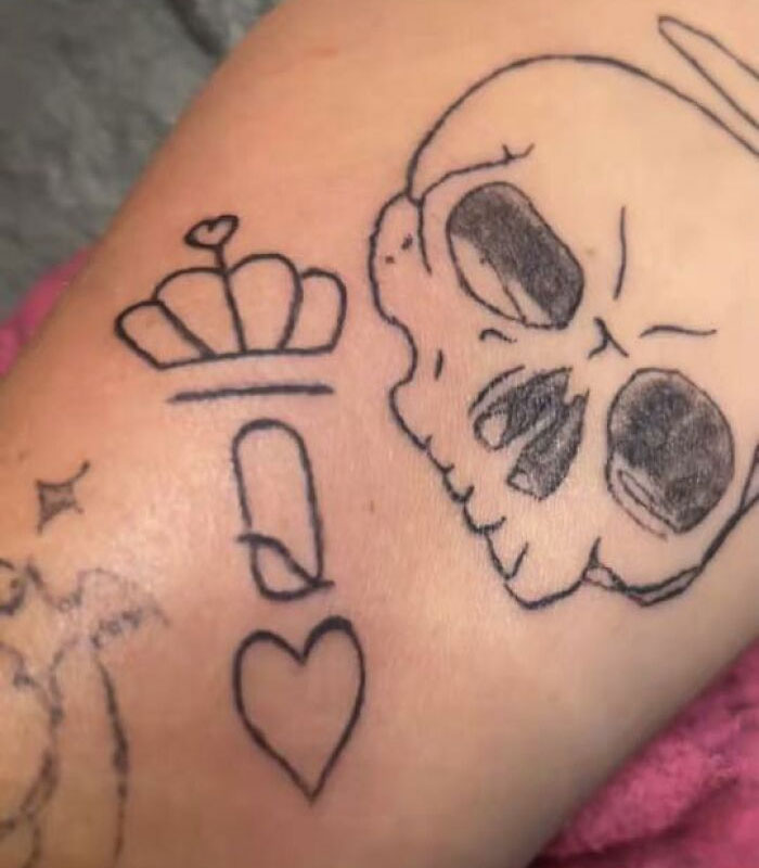 Close-up of unusual tattoos on skin featuring a skull, heart, crown, and other abstract shapes, showcasing unique body tattoos.