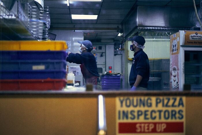 Two workers wearing masks preparing food behind a counter, illustrating people revealing longest grudges held.