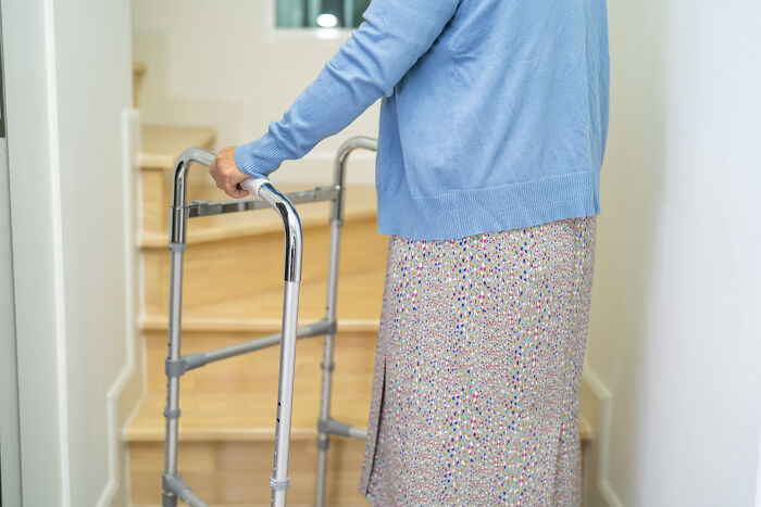 Elderly person using a walker near stairs, illustrating challenges faced by people living next to horrible neighbors.