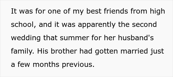 Guest wearing own wedding dress at a wedding ceremony, smiling and standing among other guests in a bright venue.