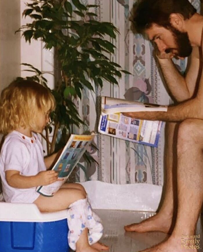 Father and child in a funny family photo moment, both reading magazines while the child sits on a potty.