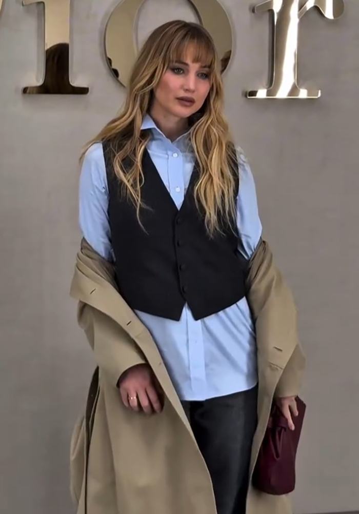 Jennifer Lawrence posing in layered outfit at Paris Fashion Week, sparking buzz around plastic surgeon topic in LA.