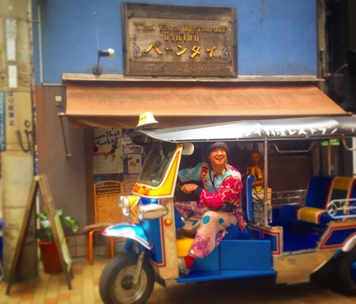 Person wearing colorful sports attire sitting in a tuk-tuk outside a Japanese restaurant, linked to tourists kicked out debate. Person wearing colorful sports attire sitting in a tuk-tuk outside a Japanese restaurant, linked to tourists kicked out debate.