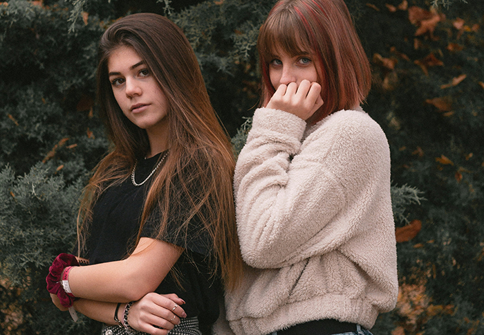 Two teenage girls standing outdoors with serious expressions, reflecting stepkids turning cruel during bio mom visits.