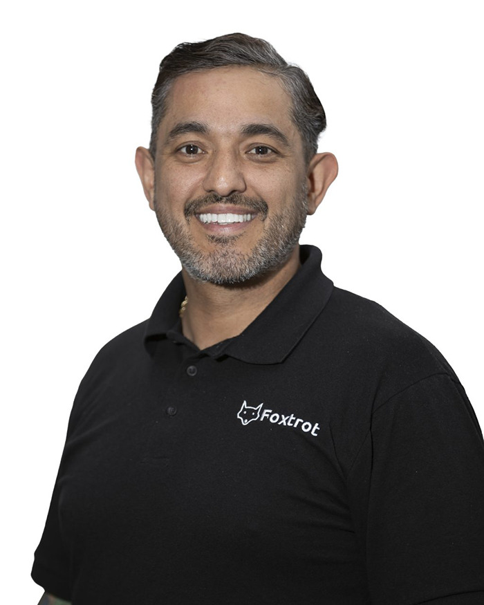 Smiling man in black Foxtrot polo shirt against white background, related to baseball Karen fired after racist rant incident.