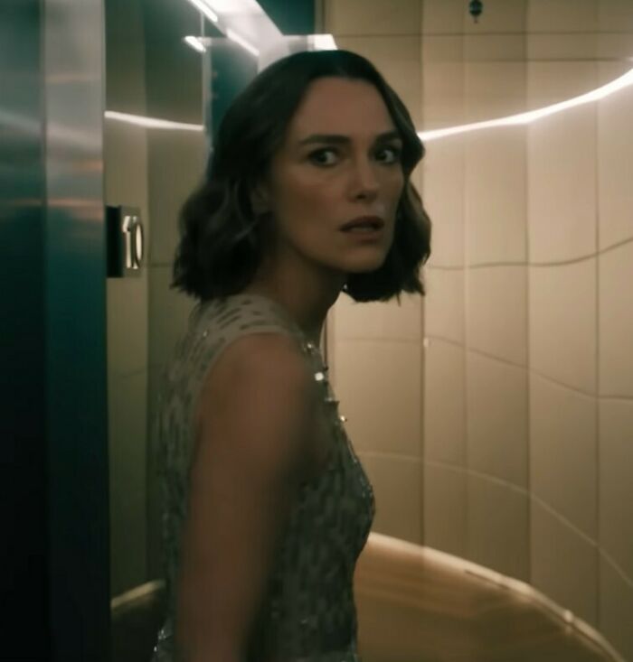 Keira Knightley in a dimly lit scene, looking back with a serious expression, related to Harry Potter boycott controversy.