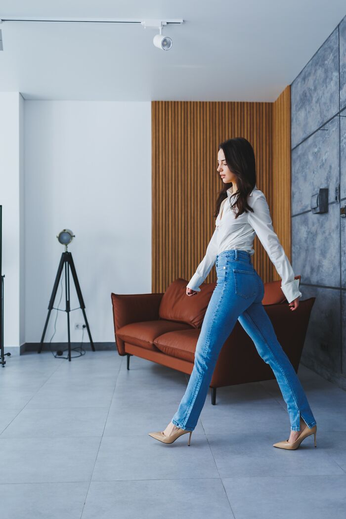Young woman walking unsteadily indoors, illustrating drunk fumbles in a modern living room setting.