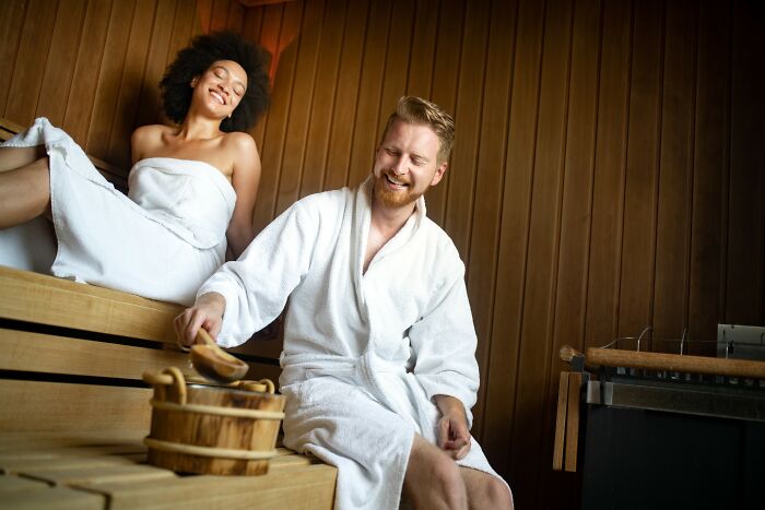 Two people relaxing in a wooden sauna, sharing unbelievable facts about their countries that are actually true.