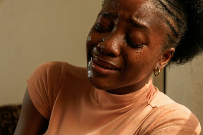 Pregnant woman crying with tears streaming down her face, showing emotional pain and distress indoors.