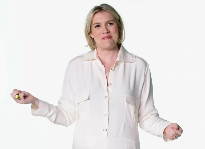 Blonde woman in a white shirt gestures while discussing Margot Robbie's provocative Wuthering Heights trailer and experts' views.