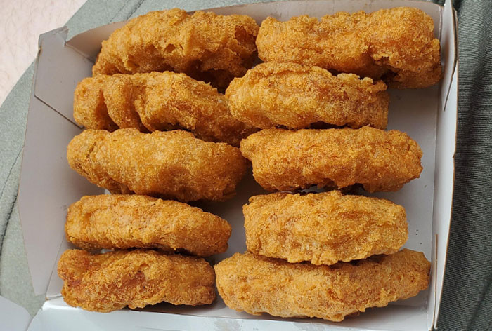 Box of crispy golden fried chicken nuggets stacked in rows, showcasing a popular loopholes food hack meal.