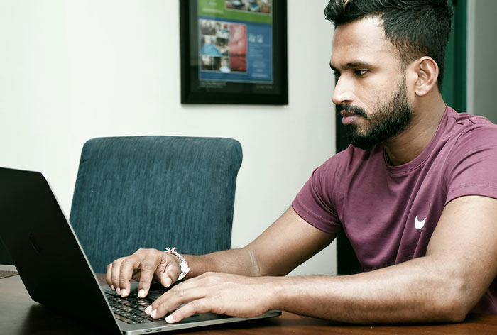 Man focused on laptop screen typing, demonstrating accidental loopholes discovery and use in everyday scenarios.
