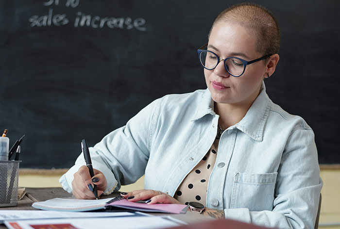 Person with glasses writing notes in a notebook, illustrating accidental discovery of loopholes and their creative use.