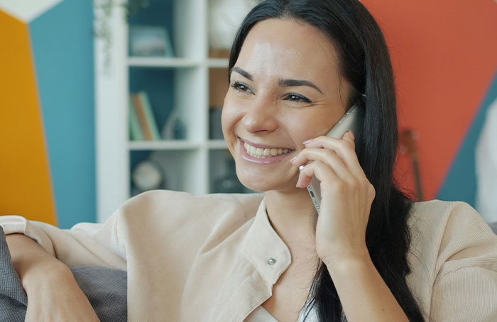 Smiling woman talking on phone while sitting in a colorful room, illustrating people discovering loopholes.