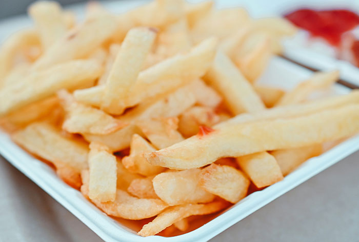 Close-up of golden French fries in a white container, showcasing a simple but tasty food loophole discovery.