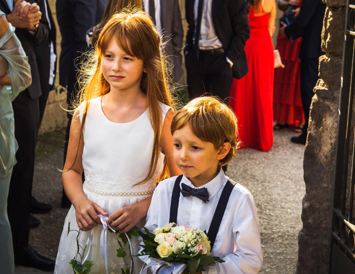 Two children dressed for a wedding during a ceremony, highlighting family attendance at a child-free wedding event. Two children dressed for a wedding during a ceremony, highlighting family attendance at a child-free wedding event.