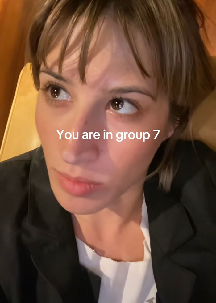 Close-up of a woman looking sideways with text overlay about group 7 in the viral TikTok trend blowing up online.