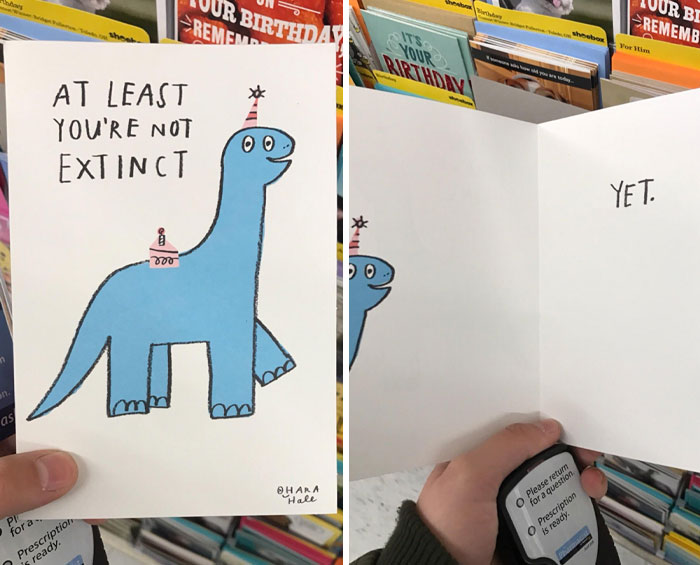 Hand holding a weird and funny dinosaur birthday card saying you’re not extinct yet in a store aisle with greeting cards.