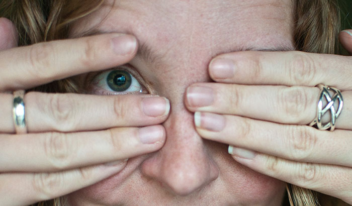 Close-up of a person partially covering their face, highlighting emotions related to botched plastic surgeries experience.