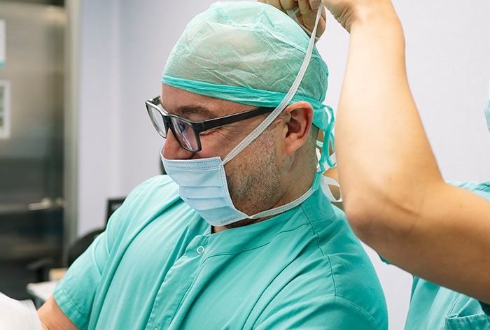 Surgeon in surgical scrubs and mask preparing for plastic surgery, highlighting botched plastic surgeries risks.
