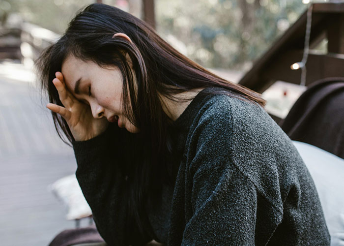 Young woman with long dark hair sitting outdoors, looking stressed, related to man&rsquo;s debt and Spiderman costume loan request.