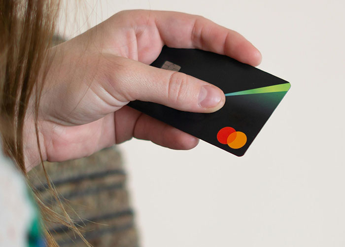 Hand holding a black credit card symbolizing debt and a loan request for an expensive Spiderman costume purchase.