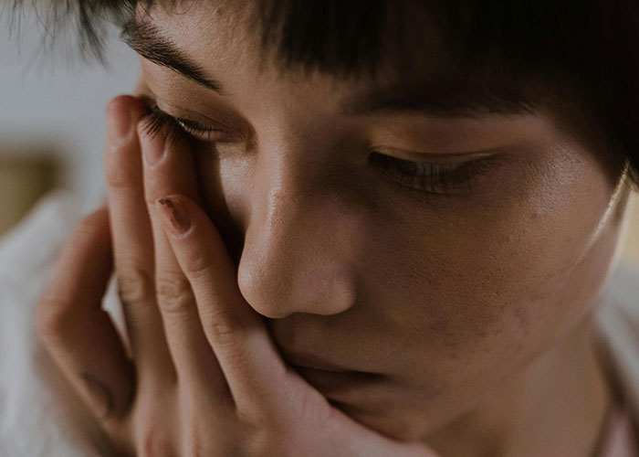 Close-up of a worried man with $5K debt contemplating asking his girlfriend to take a loan for a $1.5K Spiderman costume purchase.
