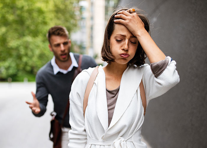 Young woman frustrated and walking away from boyfriend who is pleading outdoors, illustrating gold digger and rent money conflict.