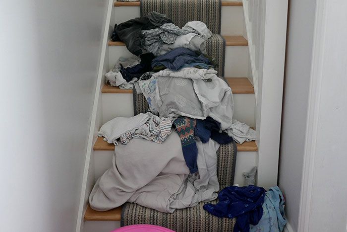 Pile of clothes scattered messily on carpeted stairs, symbolizing chaos after boyfriend destroyed girlfriend's grandma's jewelry box.