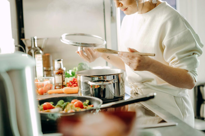 Woman cooking in a kitchen, preparing a meal while considering boyfriend mother family expectations.