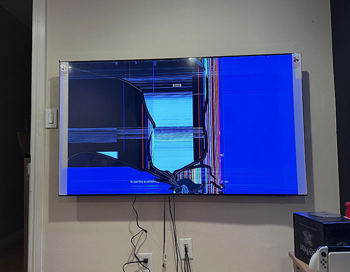 Broken TV screen with colorful distorted lines and cracks, illustrating damage caused by stepson's tantrum and related blame.