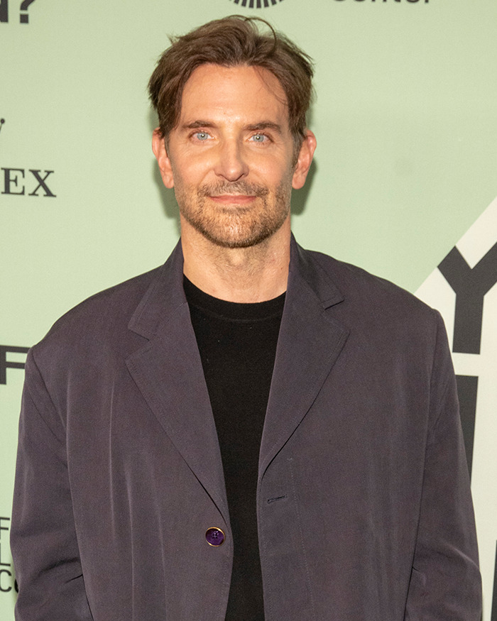Bradley Cooper with a new hairstyle and beard at an event, showcasing his radical makeover look.
