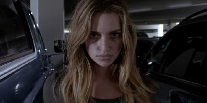 A young woman with intense expression standing between parked cars illustrating unrealistic women movie tropes.