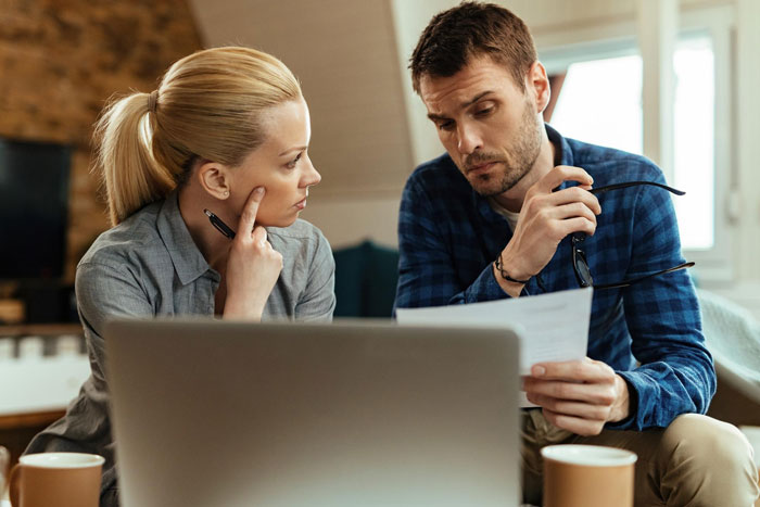 A young man and woman discussing finances with a laptop nearby, highlighting a rich golden child demanding allowance.