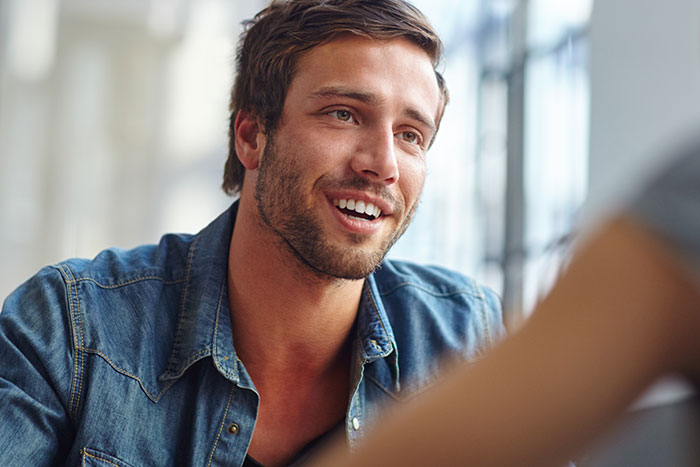 Man wearing denim shirt engaged in a conversation, reflecting shocked and horrified emotions during Thanksgiving gathering
