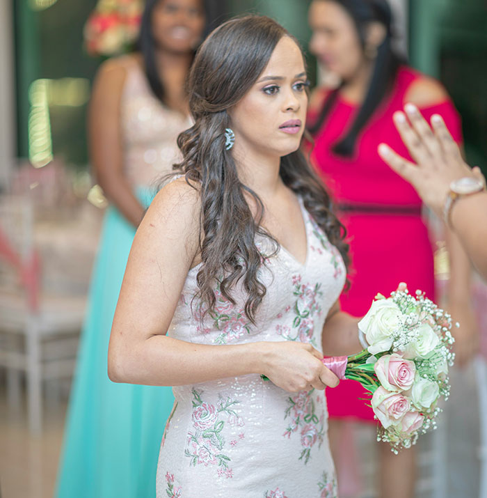 Bride looking horrified at wedding while holding bouquet, upset about cousin wearing long white dress with mom's approval.