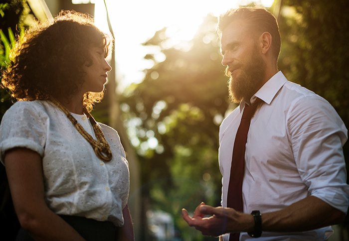 Man and woman engaged in a serious outdoor conversation, representing an obnoxious dinner guest and dreadful husband scenario.