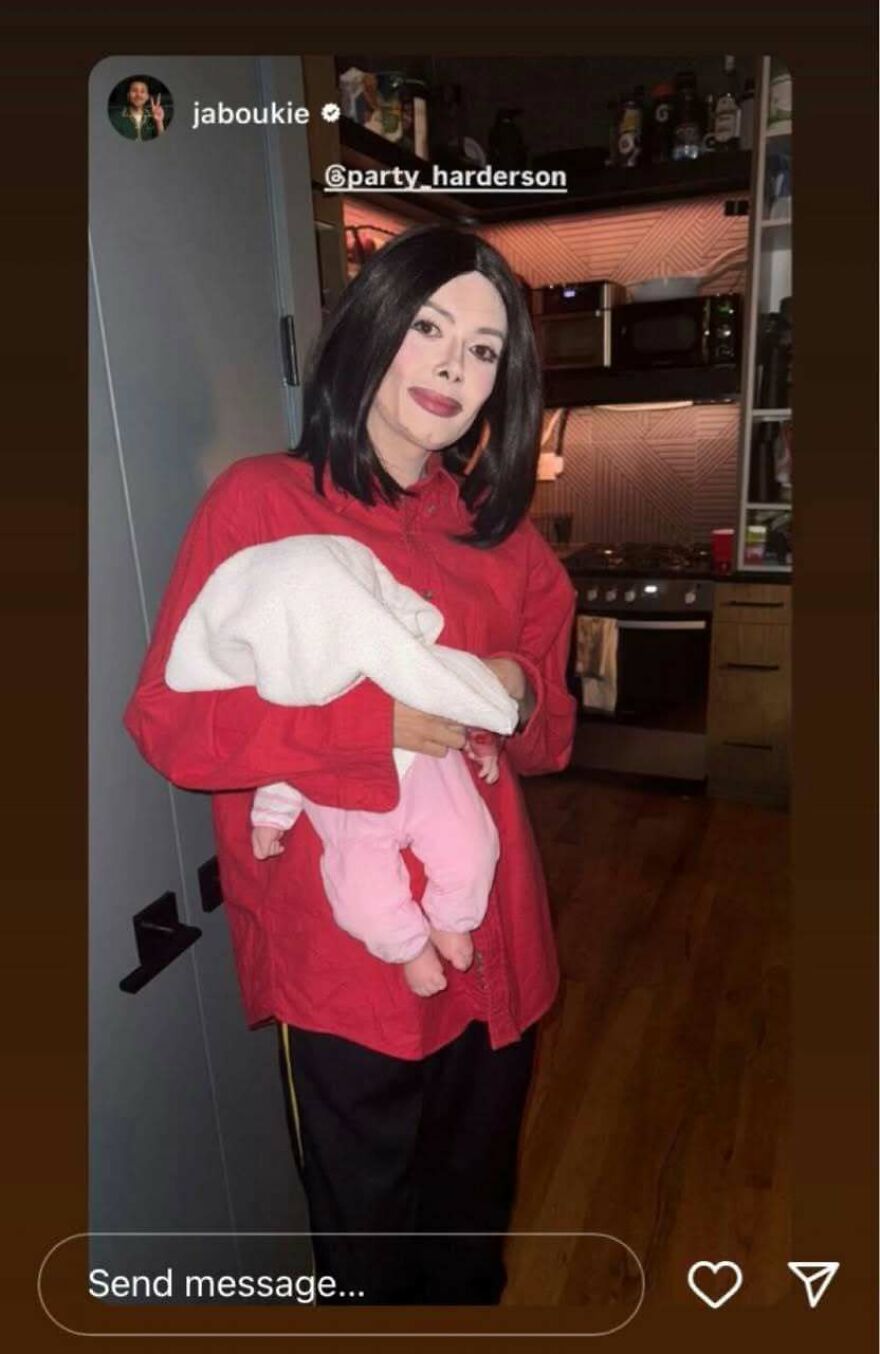 Celebrity wearing a red shirt holding a baby doll, showcasing a Halloween costume lacking common sense.