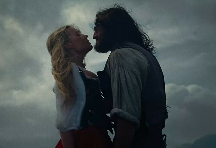 Margot Robbie and co-star in a tense scene from the provocative Wuthering Heights trailer under moody skies.
