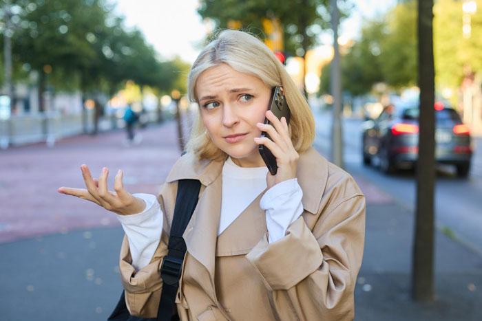 Woman talking on phone outdoors looking frustrated considering calling cops after neighbor’s disabled son raids trash repeatedly Woman talking on phone outdoors looking frustrated considering calling cops after neighbor’s disabled son raids trash repeatedly