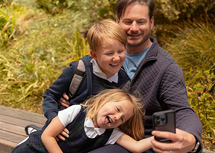 Man taking selfie with two children outside, illustrating family with four kids from different women topic.