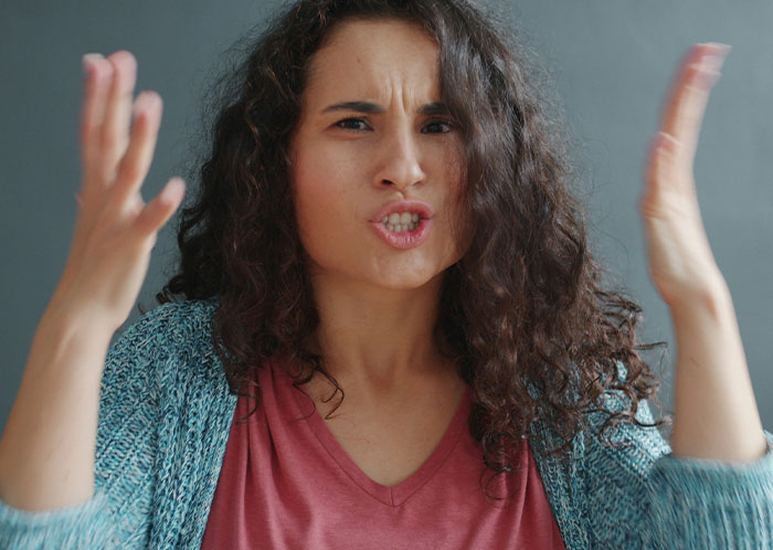 Frustrated woman gesturing with hands, expressing embarrassment while speaking to new colleague in a claimed language she knows well.