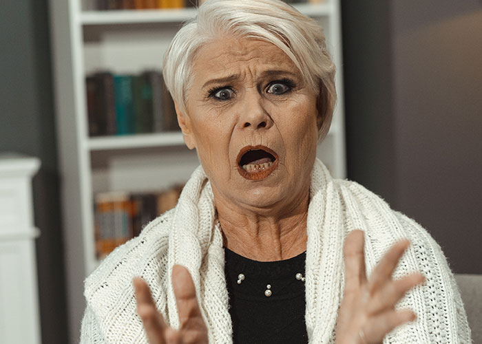 Older woman with shocked expression and hands extended, depicting a monster-in-law conflict escalating at home.