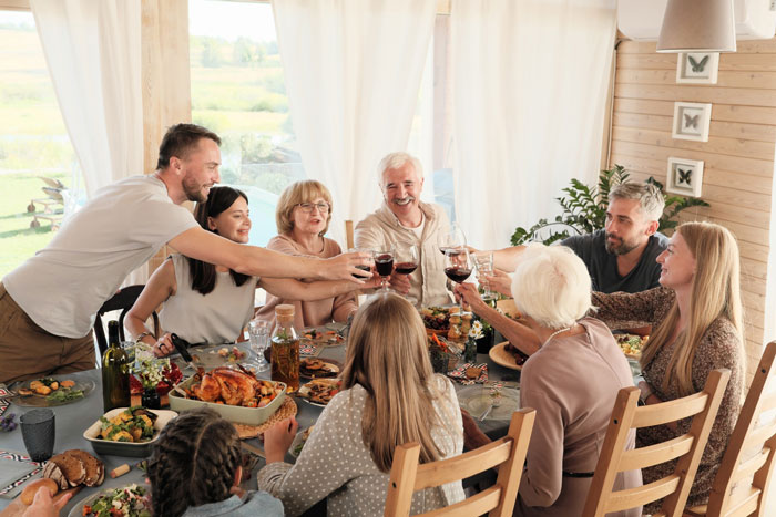 Family gathered around dining table toasting with wine glasses, highlighting themes of cheating accusations and family support.