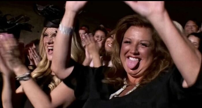 A group of women cheering and clapping enthusiastically in a lively crowd, capturing nightmare situations survival joy.