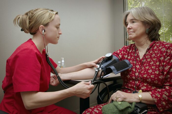 Nurse measuring blood pressure of woman in clinic, highlighting terrifying medical conditions without showing symptoms.
