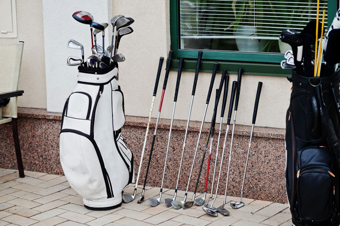 Set of golf clubs in bags and lined up outside a house, linked to rich guy trying to rip off widow.