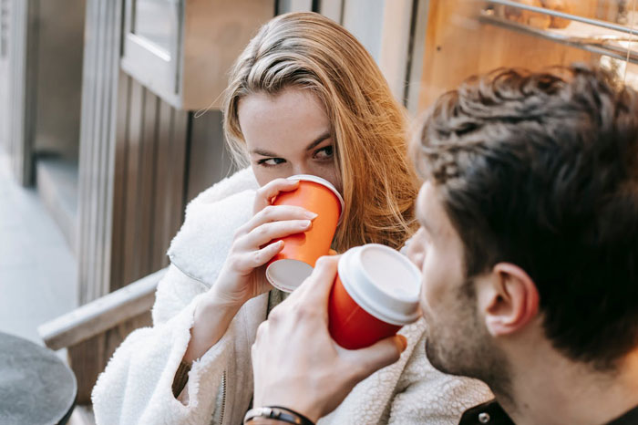 A woman and man drinking coffee together, illustrating a cheater trying to trap her ex with a baby lie.