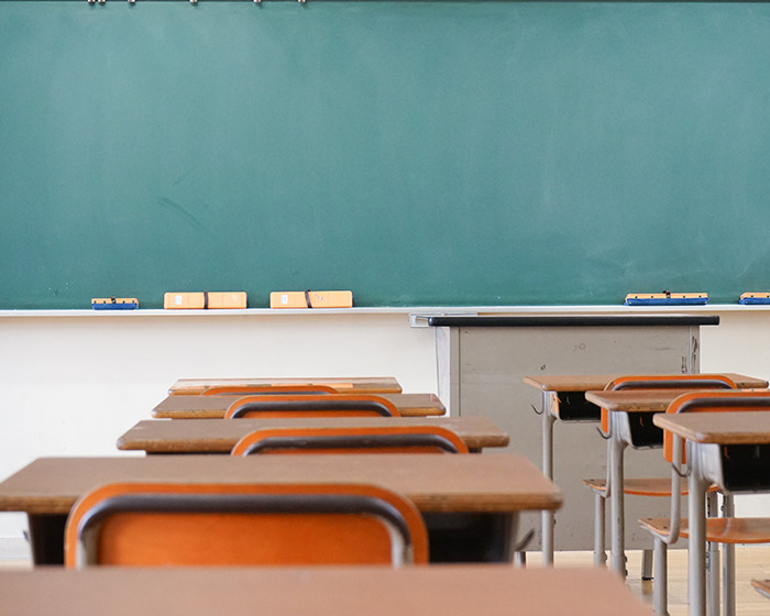 Empty classroom with wooden desks and chairs facing a green chalkboard, related to teen shocking texts with teacher story.
